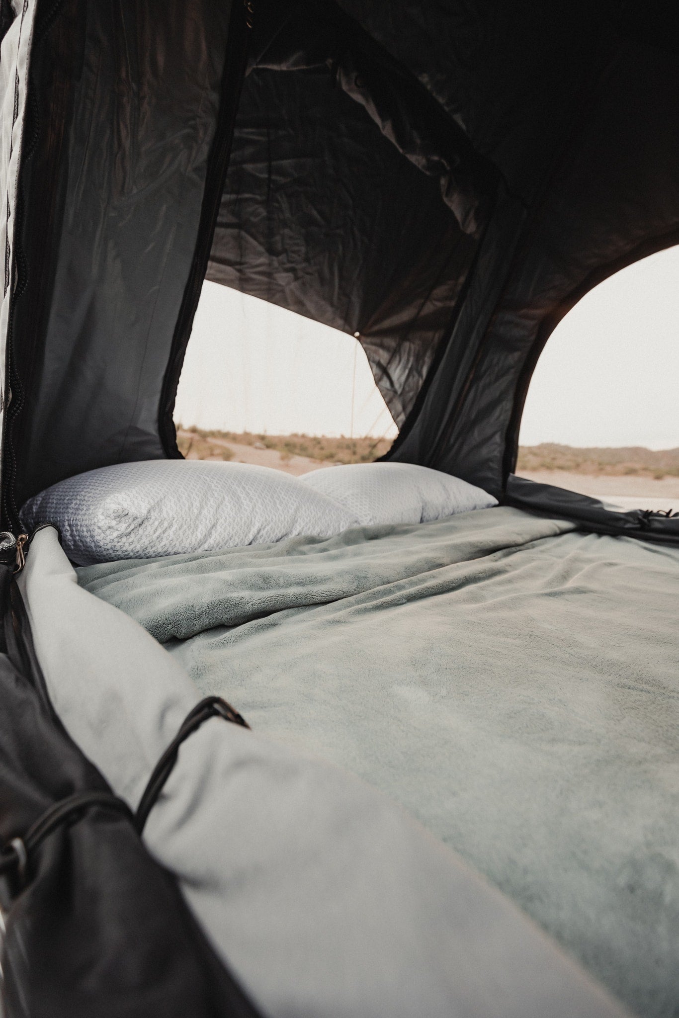 Comfortable bed inside a rooftop tent, offering a scenic view. Perfect for an RV rental camping trip. — photo 18