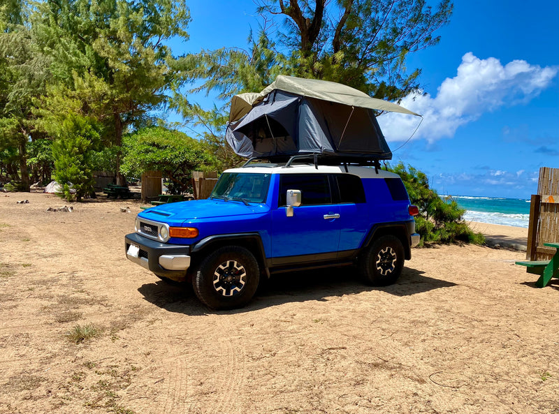 Blue FJ Cruiser with rooftop tent, ideal for an RV rental beach camping adventure. Parked on sand near the ocean. — photo 8