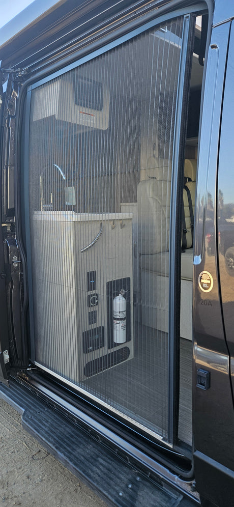 A pulled-across mesh screen door on an **RV rental** reveals its interior, including a galley counter, controls, and seating.