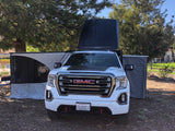 White GMC pickup truck with rooftop tent & deployed side awnings for an RV rental camping experience.