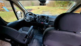 RV rental's front cabin: steering wheel, dash, and outside yard with playset visible through windshield.