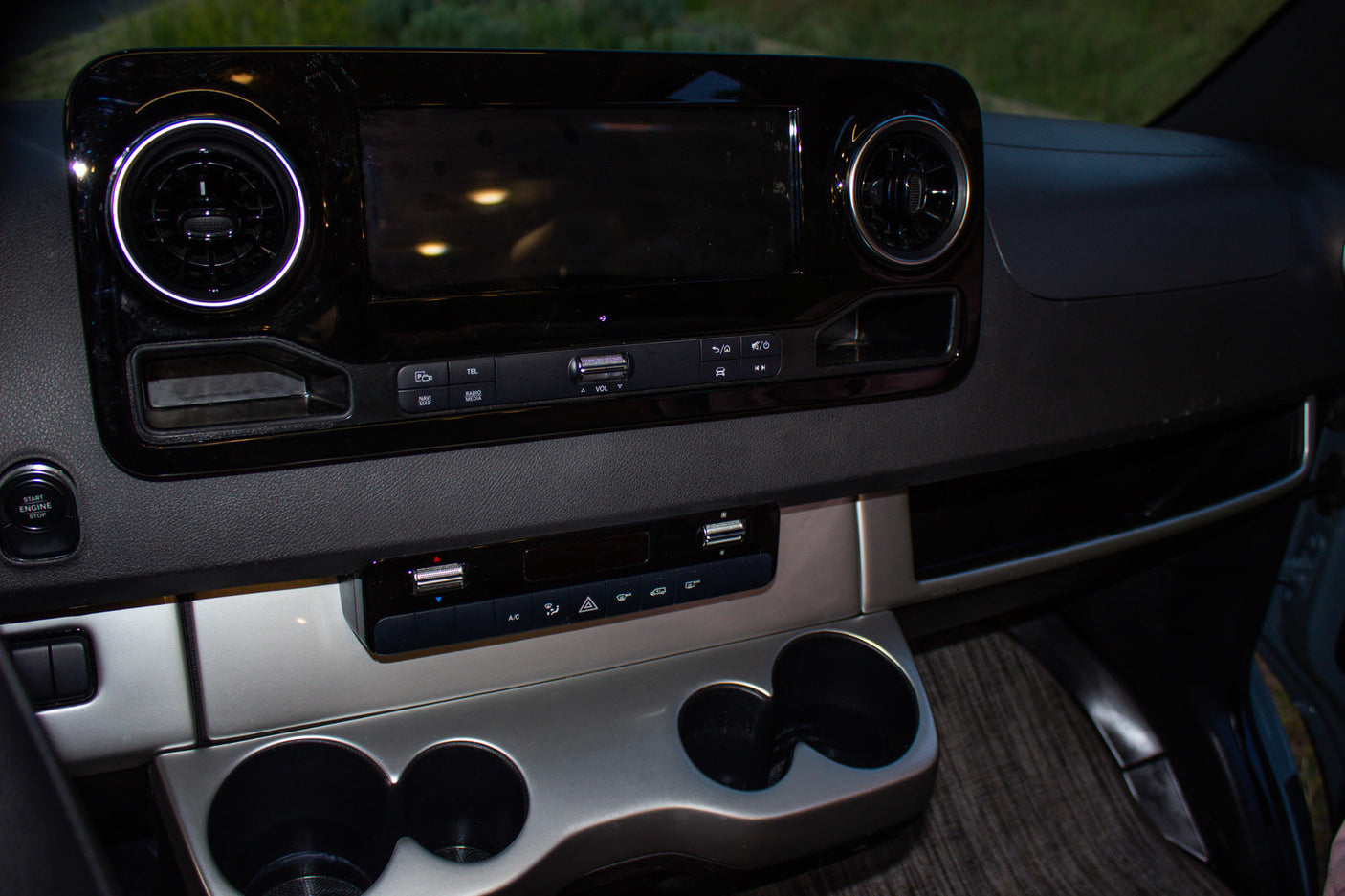 Dashboard of an **RV rental**, featuring an infotainment screen, circular air vents, climate controls, and cup holders.