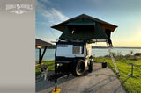 Our RV rental includes this TigerMoth camper with a rooftop tent by the lake at sunset, ready for your next adventure with your dog!