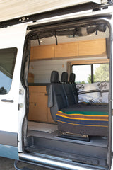 Cozy camper van interior for your next RV rental adventure, featuring custom cabinetry & versatile seating.
