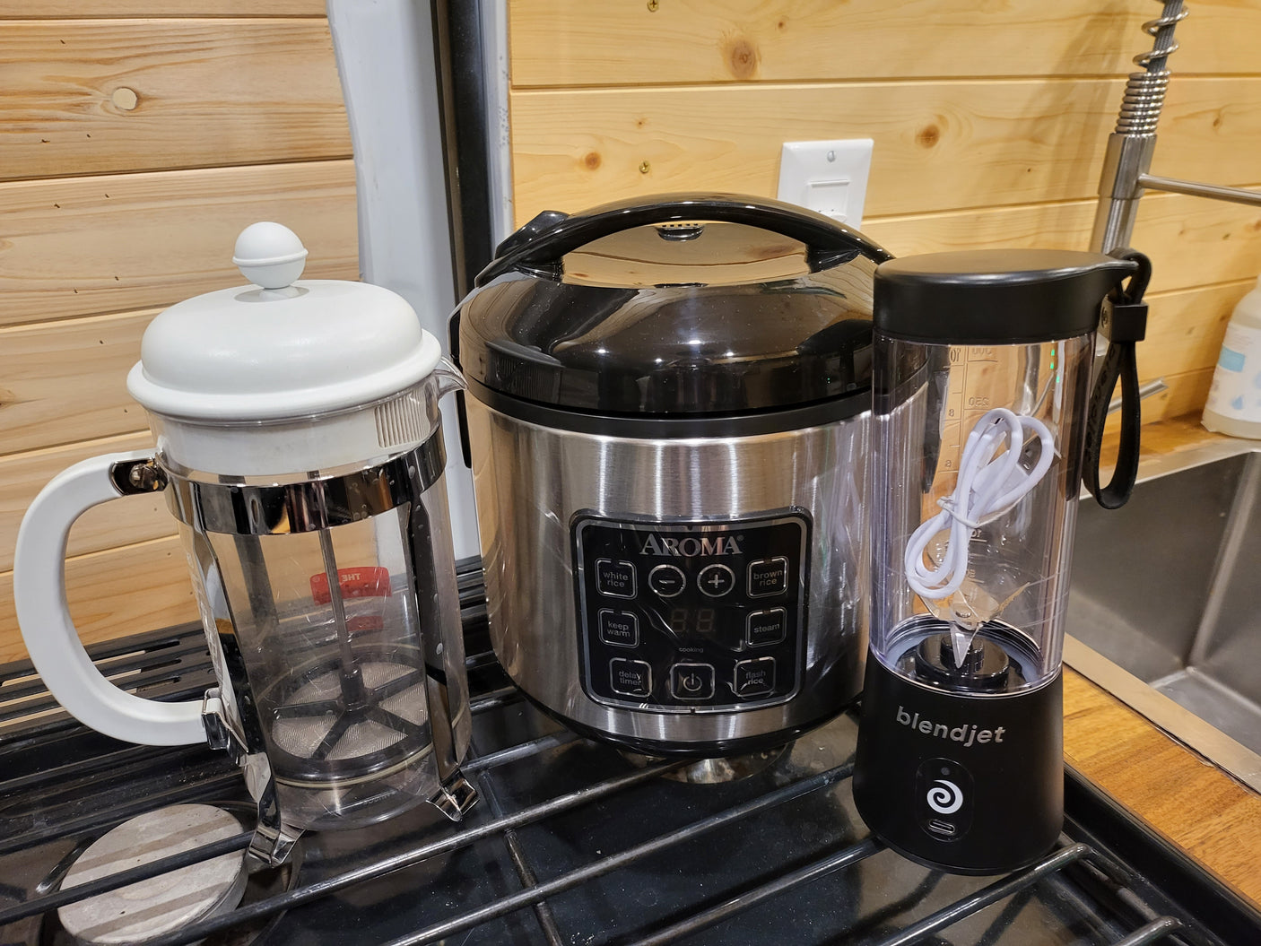 Compact kitchen essentials for your rv rental: French press, Aroma rice cooker, and BlendJet blender ready for use.