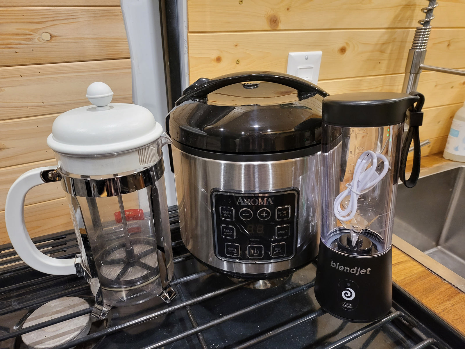 Compact kitchen essentials for your rv rental: French press, Aroma rice cooker, and BlendJet blender ready for use.