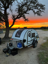 Vibrant sunset illuminates a white T@G teardrop RV rental, perfect for scenic camping.