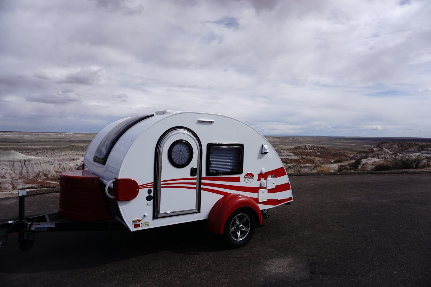 Experience outdoor adventure with this RV rental teardrop trailer parked in a vast, arid landscape under cloudy skies. — photo 8