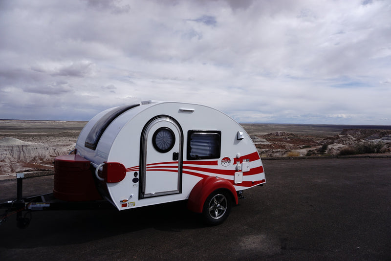 Experience outdoor adventure with this RV rental teardrop trailer parked in a vast, arid landscape under cloudy skies. — photo 8