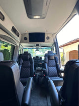 Luxurious RV rental interior showcasing premium black leather seating, a ceiling TV, and custom finishes for travel comfort.