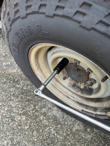 Tire maintenance on an RV rental: a wrench loosening rusty lug nuts on a General tire and weathered wheel.