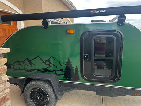 A vibrant green teardrop RV rental, equipped with an ARB Touring awning, mountain graphics, and sturdy off-road tires.