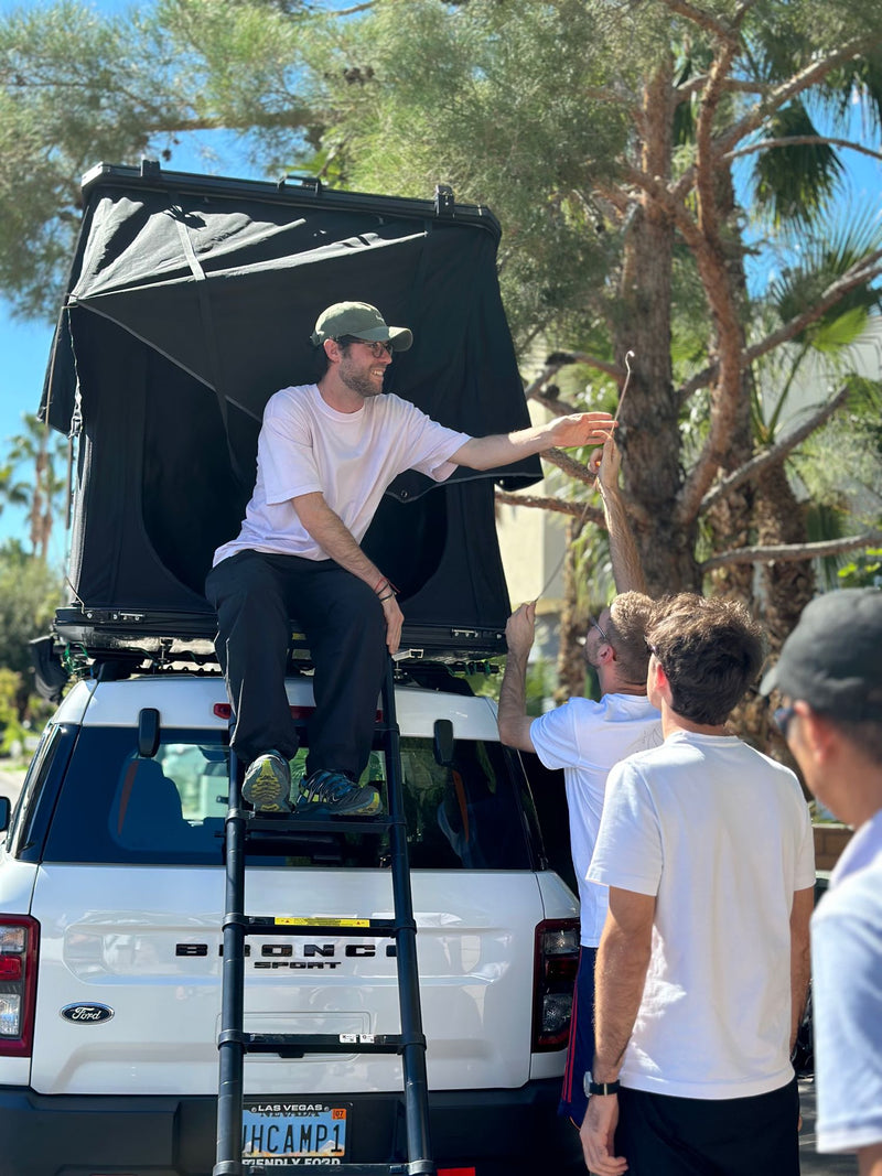  with search/destination options. Dashboard controls visible. Ideal for travel.|Four happy men with their JH Campers RV rental SUV & roof tent — photo 13
