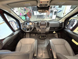 Inside a modern camper van (RV rental) cockpit. View of dashboard, steering wheel, and front seats, ready for adventure.