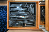 Neatly organized kitchen utensils drawer with cutlery & cooking tools, ideal for an rv rental. Visually, black tray in wooden drawer.