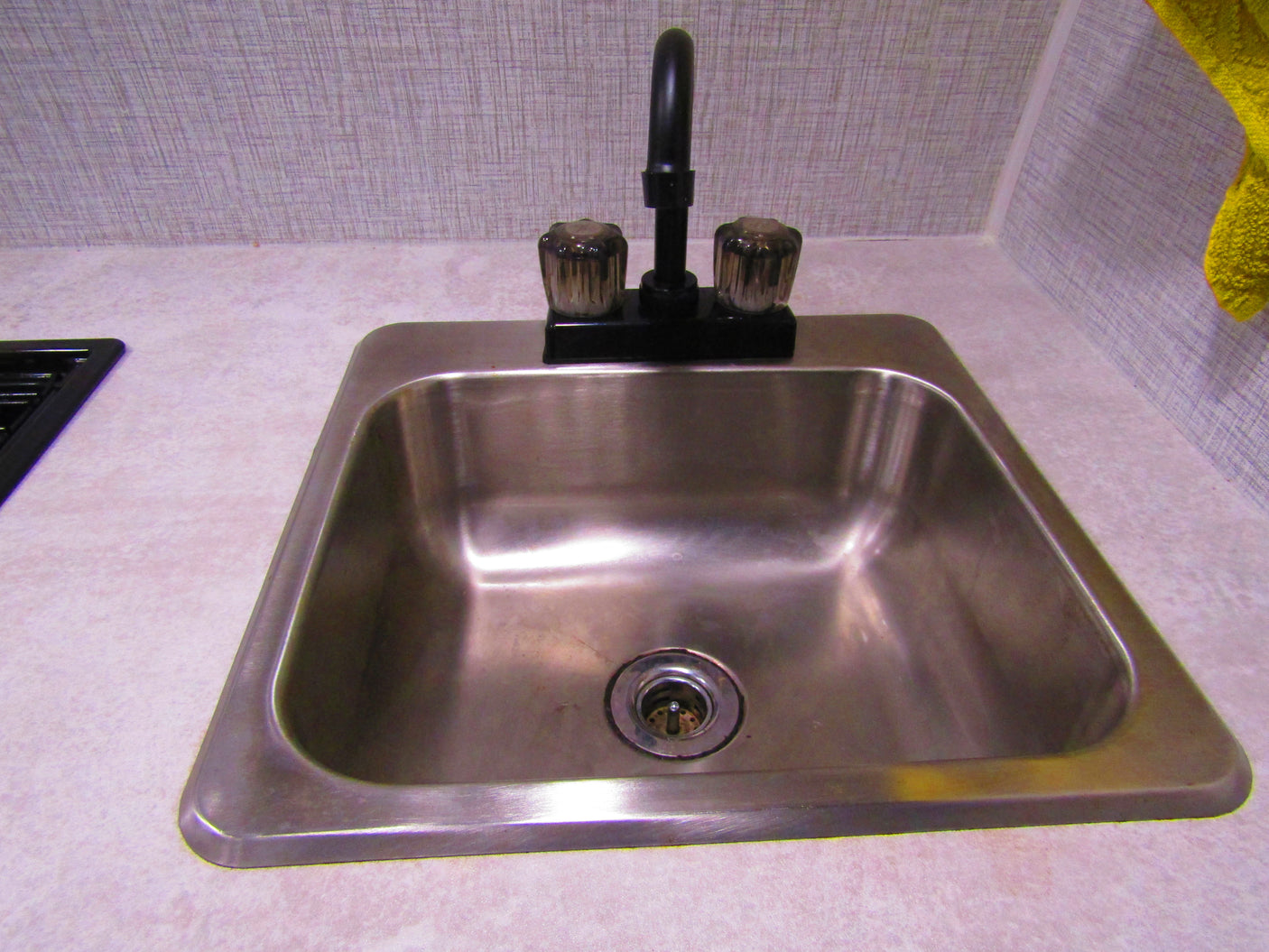 Compact stainless steel sink and faucet in an RV rental kitchen, perfect for travel and camping meals.