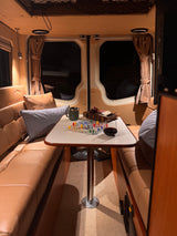 An inviting RV rental interior, showing a table set for a game, wine, and snacks between leather benches.