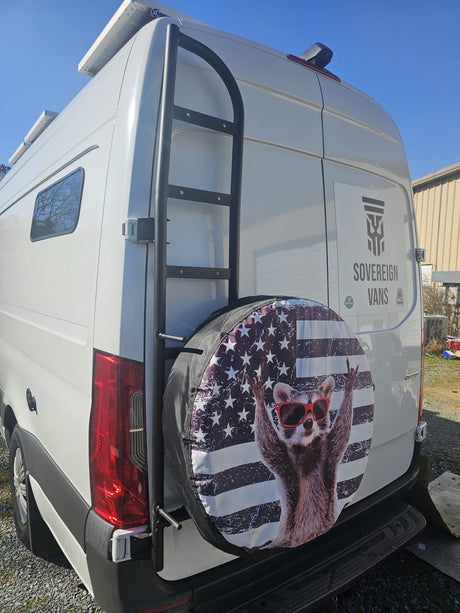 This white custom rv rental van features a rear ladder, solar panels, and a fun patriotic raccoon tire cover.