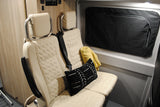 Cozy RV rental interior with light quilted passenger seats, a seatbelt, a window cover, and a throw pillow.