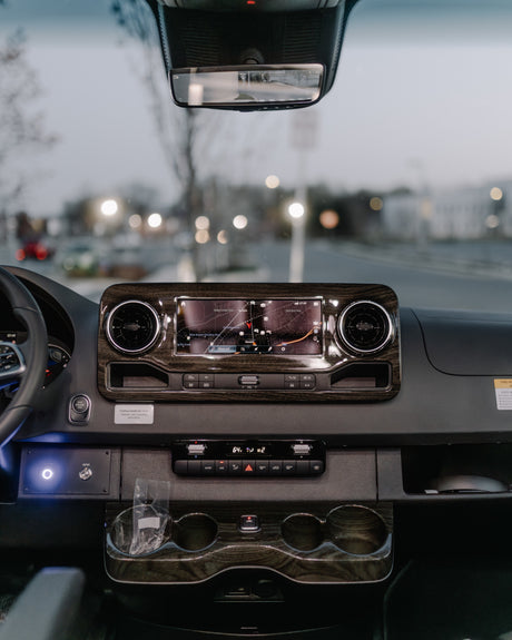 This RV rental's modern dashboard is seen from inside, showing the navigation screen, climate controls, and steering wheel.