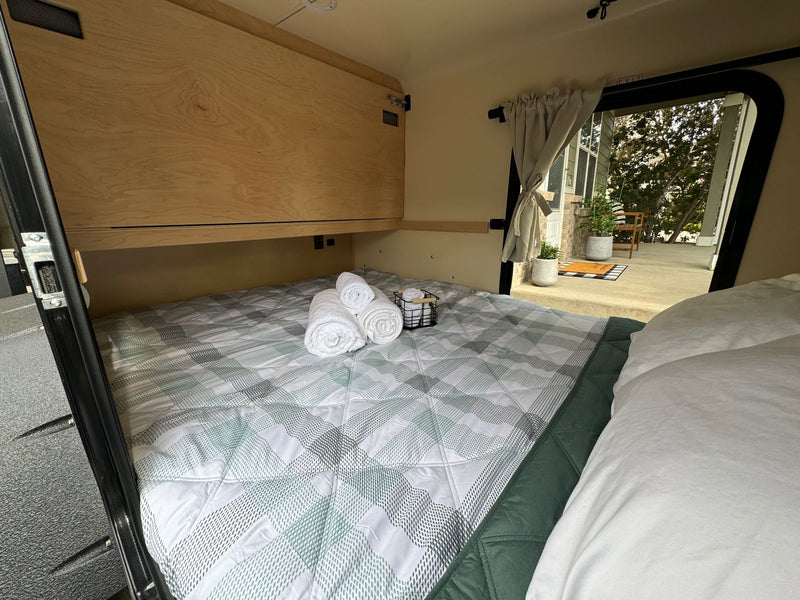  and an open hatch revealing an outdoor patio. Ready for adventures!|Cozy RV rental interior: A compact bed with plaid bedding — photo 5