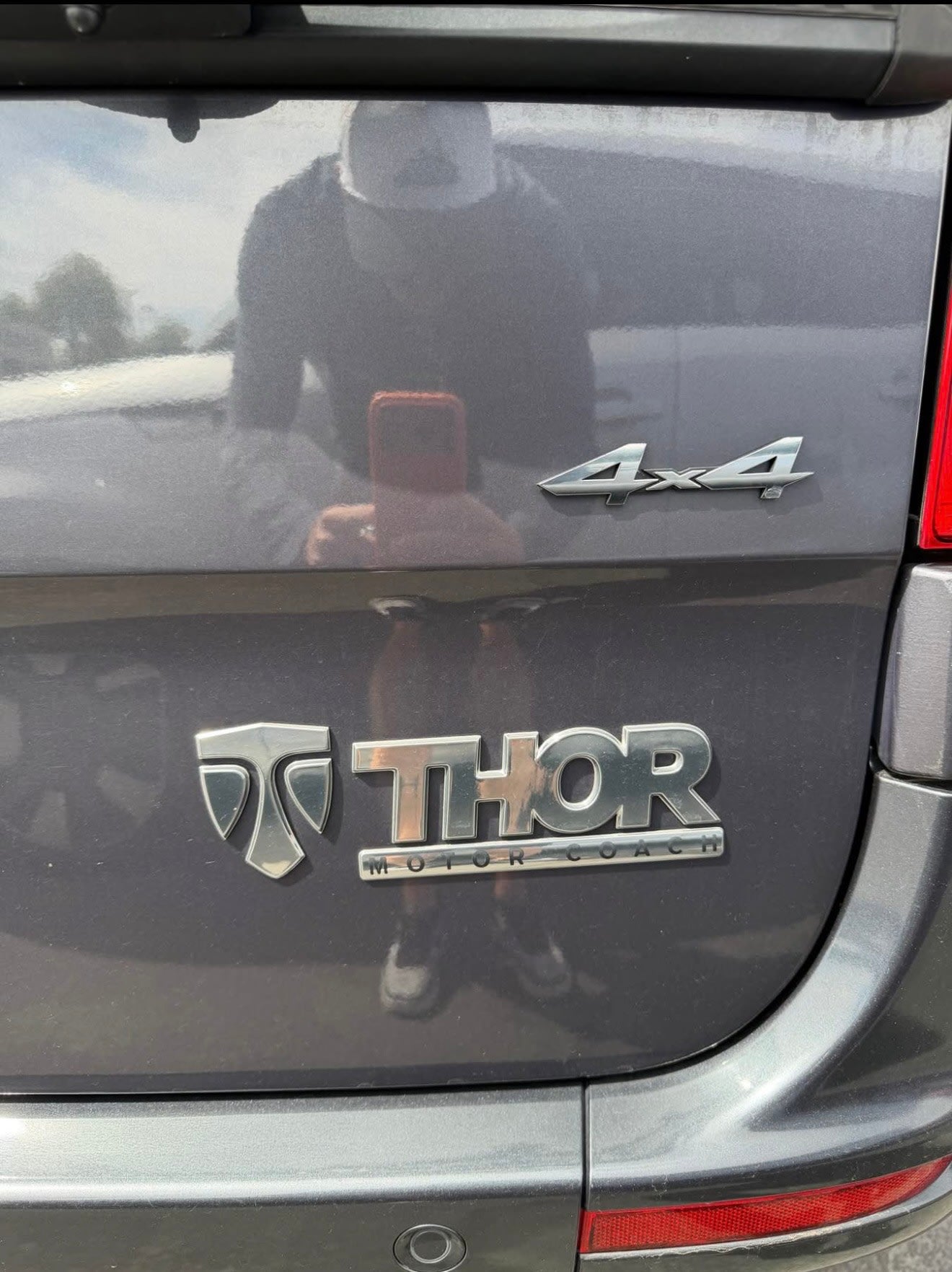 Rear of a dark gray Thor Motor Coach 4x4, reflecting the photographer. Great choice for an RV rental.