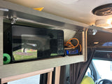 Compact RV rental kitchen setup featuring a built-in microwave, BOSS Bluetooth stereo, and overhead storage.