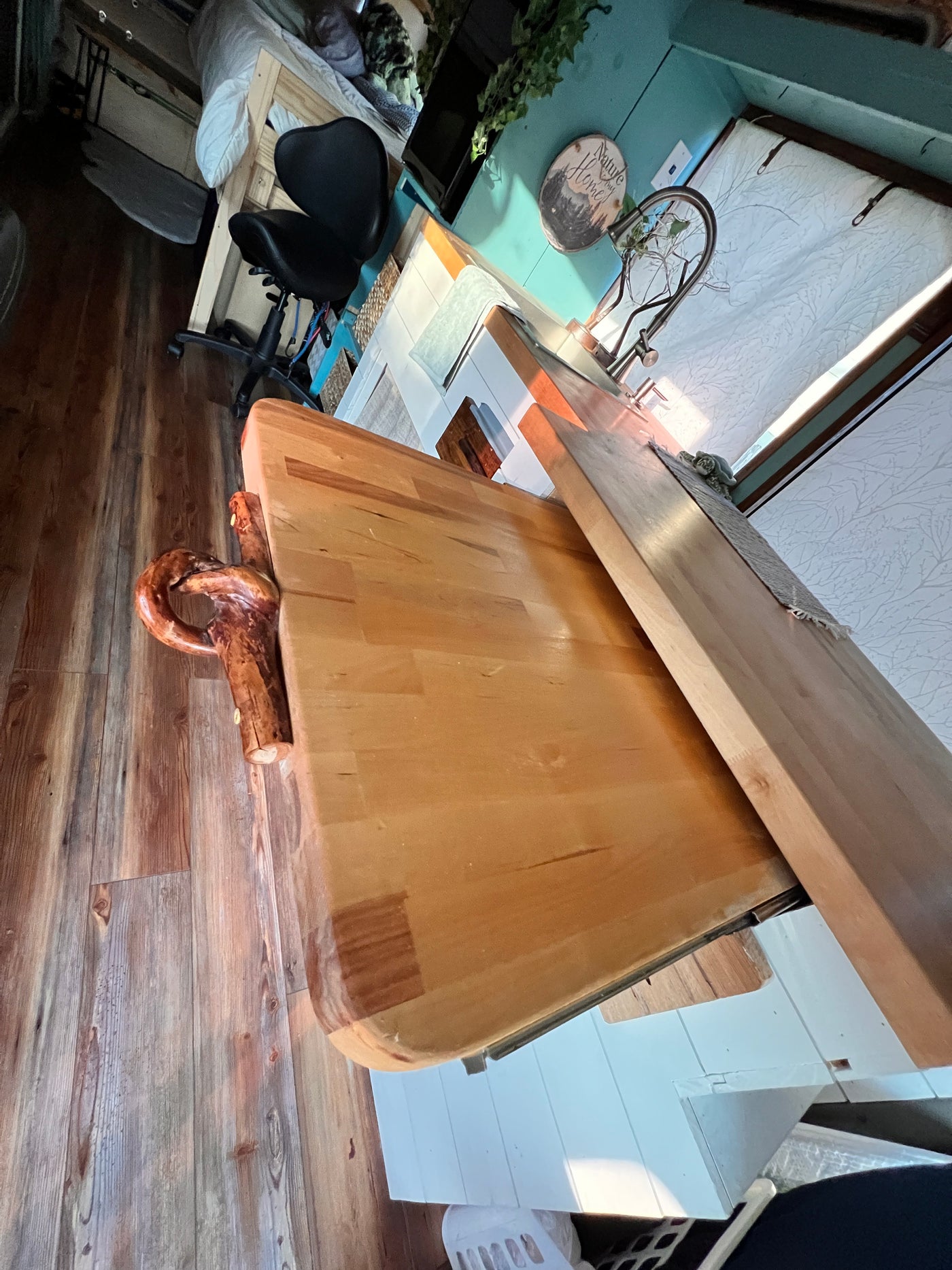 Cozy rv rental interior: warm wood tones, a unique table with a gnarled leg, kitchen, and bed. Perfect compact living. — photo 16