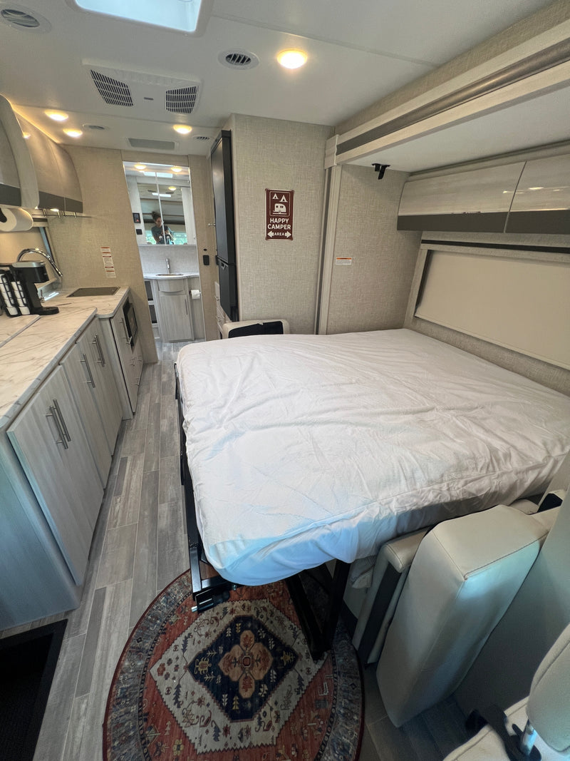 View the inviting interior of an RV rental: a modern compact kitchen, comfortable bed, and accessible bathroom. — photo 14