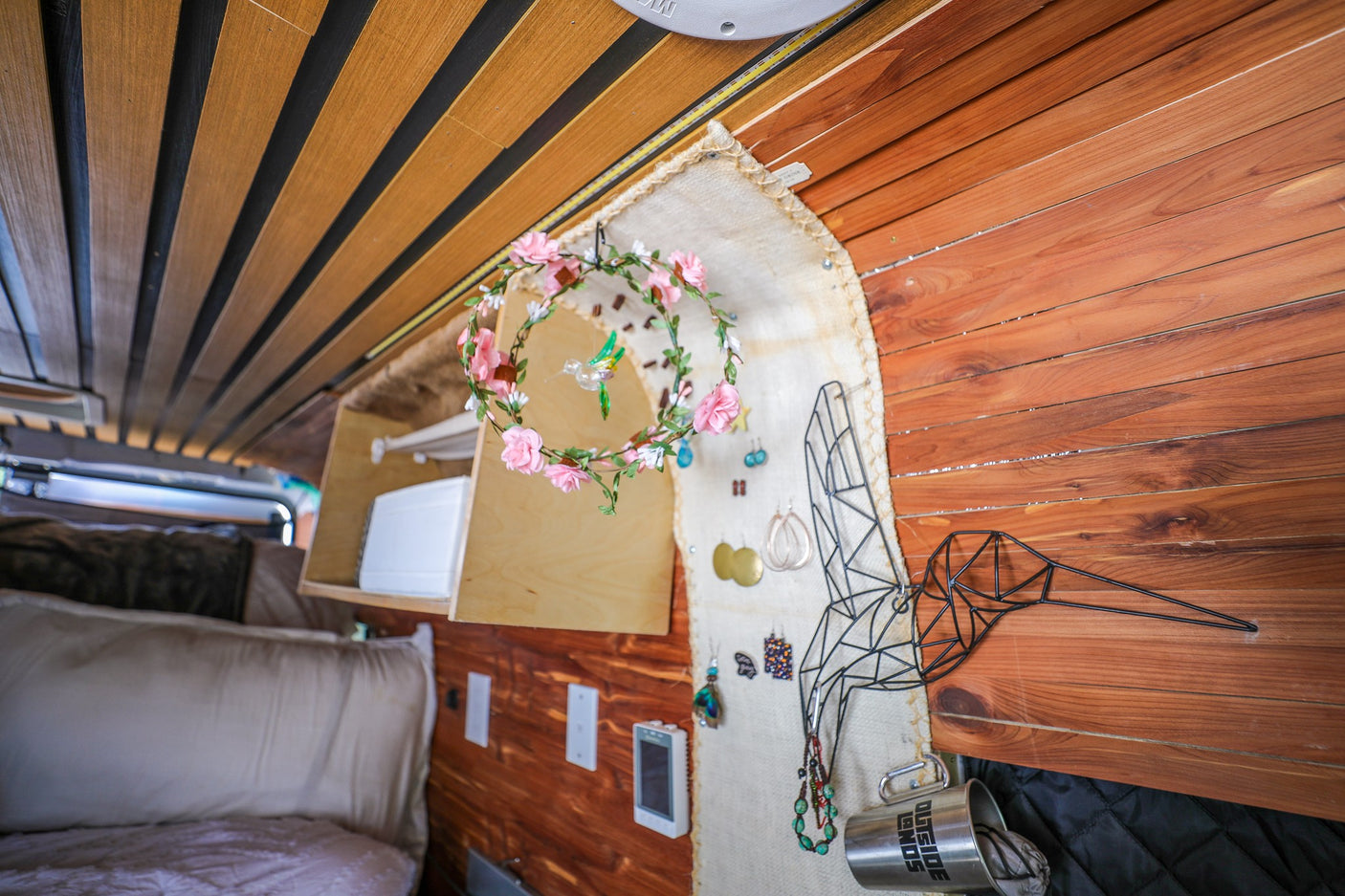 Personalized rv rental interior featuring custom wood paneling, a creative jewelry display, and cozy bed area.