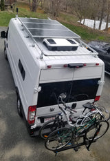 This white RV rental camper van features rooftop solar panels, AC, and a bike rack, ideal for road trips and adventure.