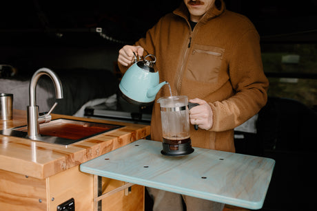 A traveler pours coffee in a cozy RV rental kitchen, perfect for on-the-go adventures.