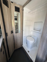 Compact RV rental wet bath with toilet and shower inside a camper van.