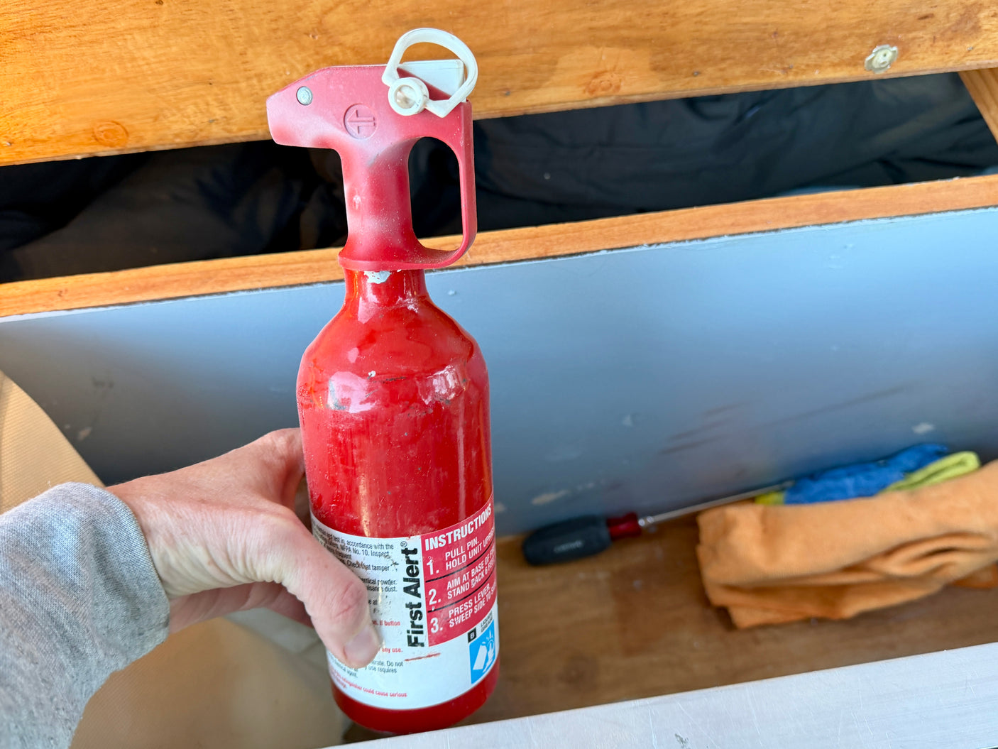 Safety first! An essential First Alert fire extinguisher with instructions, held in an RV rental's storage compartment.