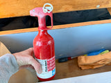 Safety first! An essential First Alert fire extinguisher with instructions, held in an RV rental's storage compartment.