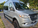 Silver Mercedes-Benz Sprinter RV rental: custom camper van with off-road tires and running boards, parked outside.