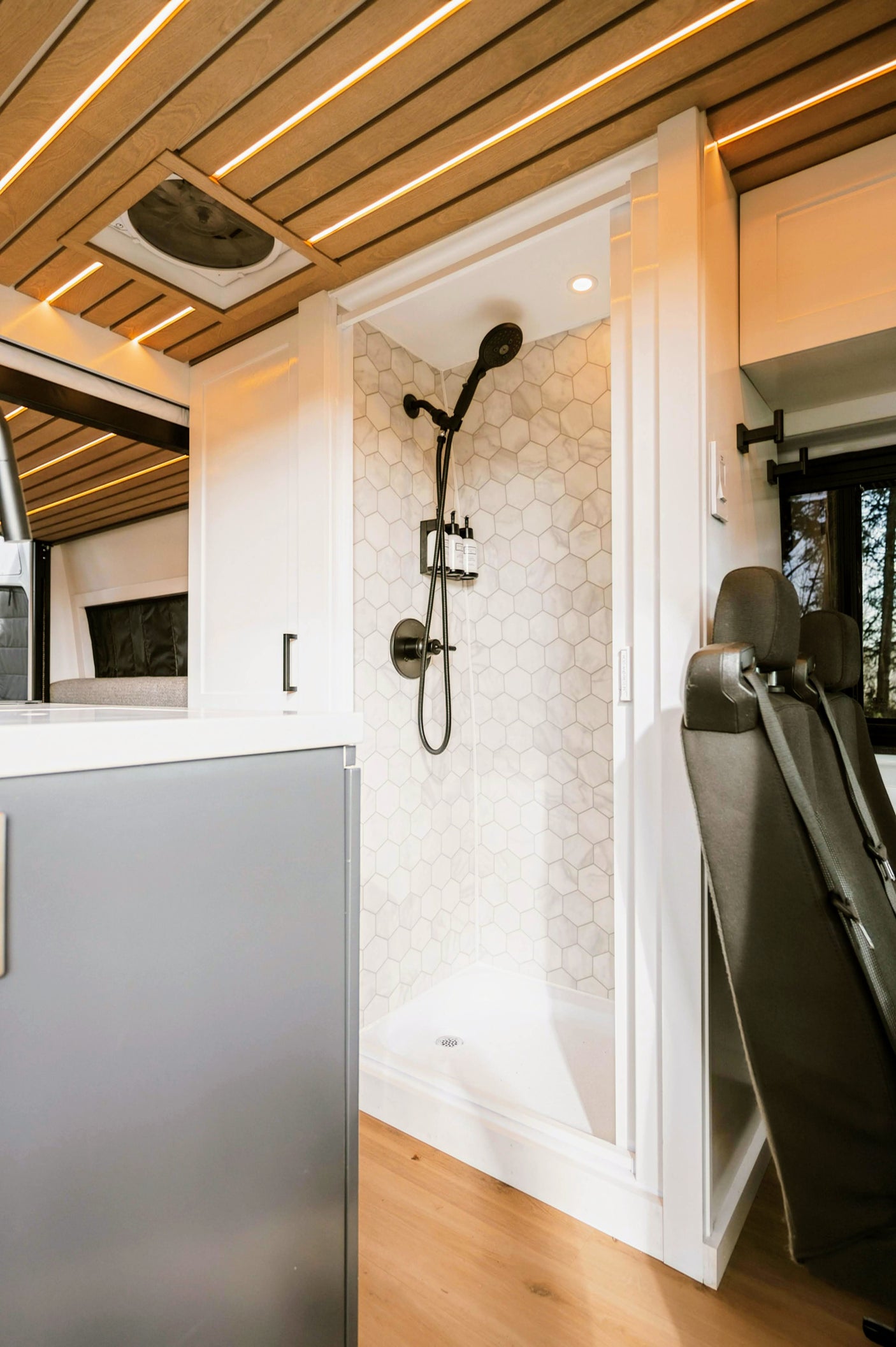 This RV rental boasts a full shower with hexagon tiles, bright LED ceiling, and spacious, inviting interior.