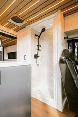 This RV rental boasts a full shower with hexagon tiles, bright LED ceiling, and spacious, inviting interior.