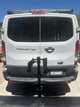 White Ford Transit van with DANCHEL OUTDOOR rooftop awning & bike rack, perfect for an rv rental adventure.