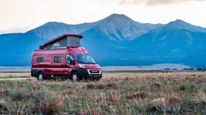  complete with a fire pit and chair.|Experience van life! Red pop-top rv rental parked by a river — photo 1