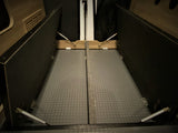 Inside an RV rental: A recessed channel with gray textured floor is formed by two open black panels, supported by gas struts.