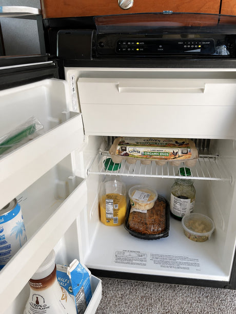 Inside an RV rental fridge: Organic eggs, juice, half & half, and ready-to-eat meals, perfect for road trip convenience.