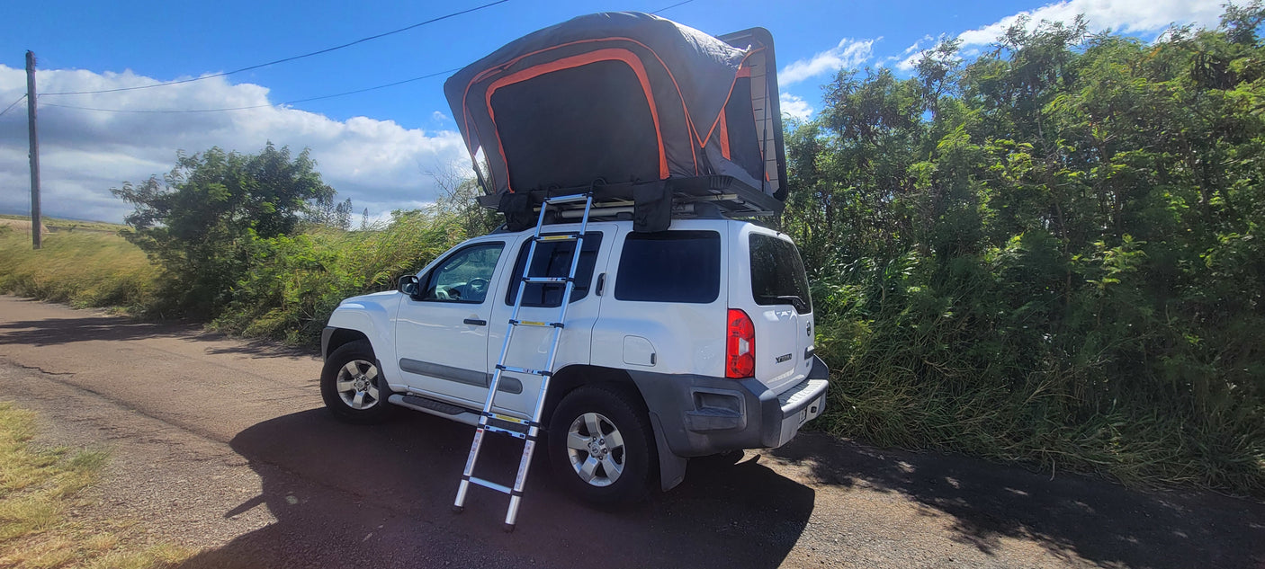 White Nissan Xterra SUV with a deployed rooftop tent and ladder, ideal for your rv rental adventure.
