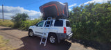 White Nissan Xterra SUV with a deployed rooftop tent and ladder, ideal for your rv rental adventure.