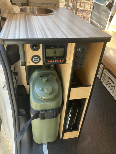 RV rental utility setup: compact sink, solar charge controller (MT50), USB/AC power outlets, and a large water jug.