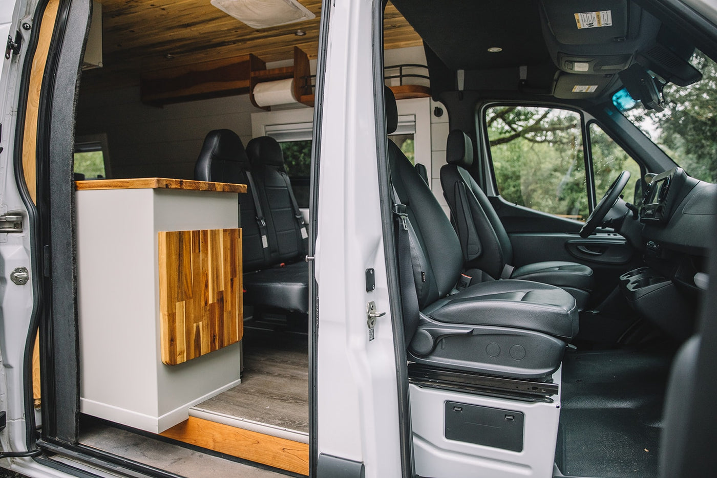  revealing its custom wood-accented interior.|A white camper van rv rental with its side door open — photo 5