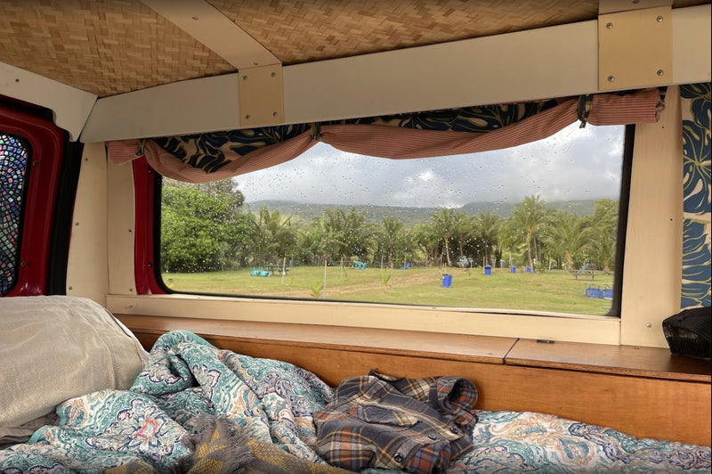 Cozy RV rental interior: A bed faces a rain-streaked window overlooking palm trees and distant mountains. — photo 19
