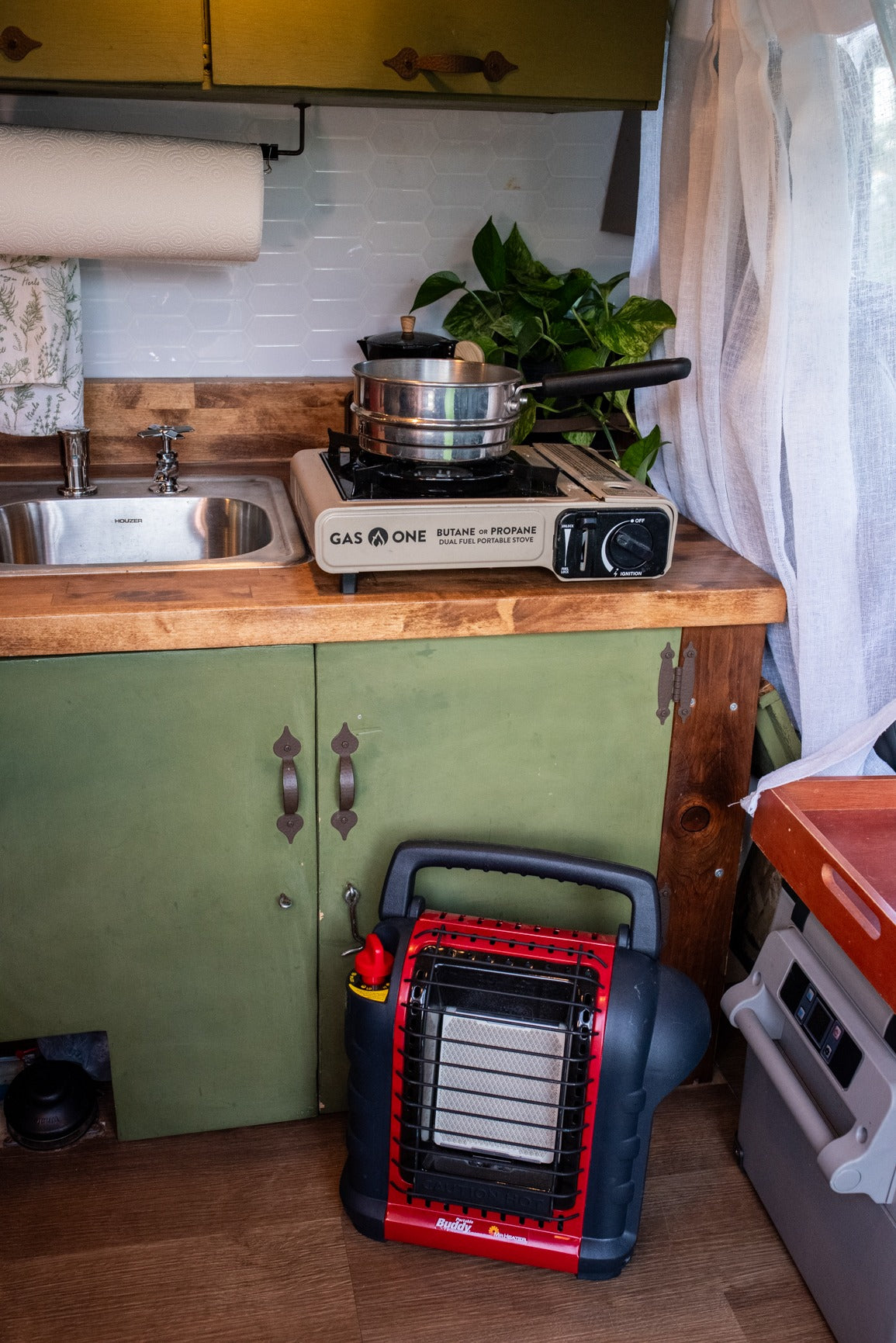 Compact RV kitchen with a portable stove, sink, and Mr. Buddy heater. Ideal for an rv rental adventure.