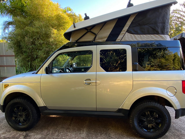 Silver Honda Element with a pop-top camper, ideal compact RV rental for adventurers.