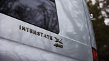 Rear view of a white Airstream Interstate X 4WD RV, ideal for an rv rental. Water droplets on the vehicle's surface imply rain.